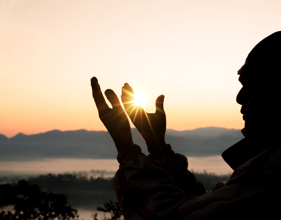 Silhouette of a man raising his hands to make du'a.